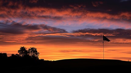 Fototapeta premium Silhouette of a lone golf flag against a dramatic sunset sky