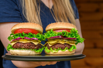 Dwa cheeseburgery z wołowina niesione przez kelnerkę na tacy © Paweł Kacperek