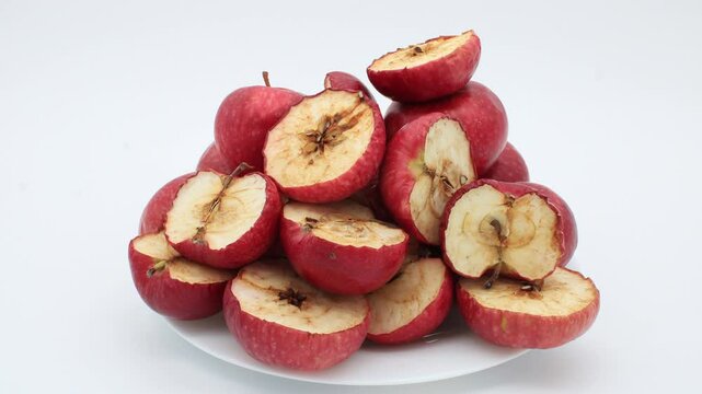 Super time lapse of pile of poor or low quality apples dehydrating and going bad after placing whole and split in halves fruits on porcelain white plate inside lightbox