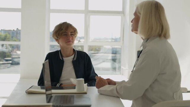 Ill boy child suffering from cold flu allergy infection sitting at doctor. Sick teenager blows sneezes wipes snot into napkin. Teenage guy having cold flu, suffering from bad symptoms. Doctor helps