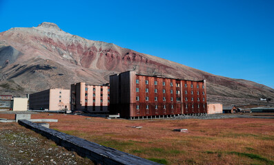 Abandoned buildings in Pyramiden under clear blue skies in Svalbard during daylight hours
