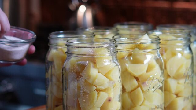 Canning potatoes for food storage. Using a pressure cooker method of canning potatoes after cleaning, chopping and dicing them and putting in mason jars for the winter food supply. Using a colander.
