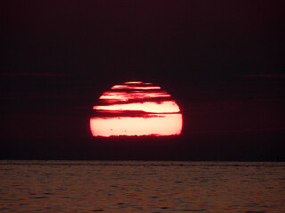 extremely zoomed sun at the sunset by the sea
