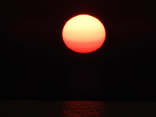 extremely zoomed sun at the sunset by the sea