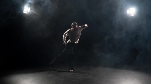 Energy of movement, woman dancing in dark studio, slow motion shot in darkness. Joyful female dancer dancing actively in dance hall, hip-hop dance style and contemporary choreography, hobby in pastime