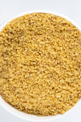 Macro bulgur cracked wheat in a plate on a white background