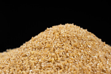 Pile of raw uncooked wheat groats on a black background