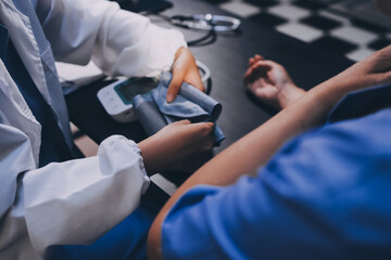 A doctor taking a patient's blood pressure. The patient's arm is equipped with a blood pressure cuff, and the doctor is using a blood pressure monitor.
