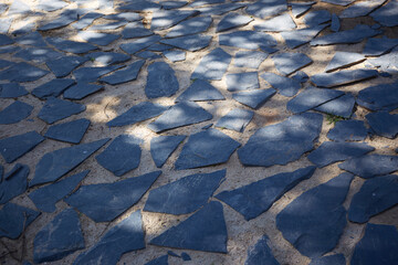 Dark stone walkway in the park with sunlight and shadow on the ground