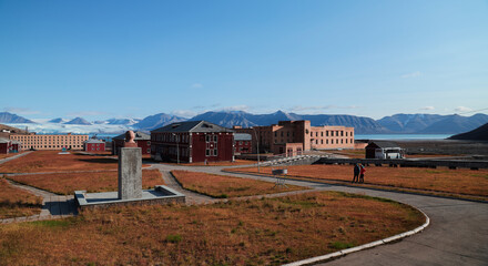 Exploring the abandoned buildings of Pyramiden in Svalbard under a clear blue sky