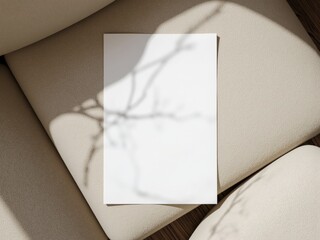 blank a4 paper on beige boucle fabric sofa, warm directional lighting casting bold shadows for a minimalist and luxurious aesthetic. Paper mockup