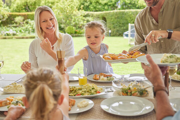 Family, lunch and father serving food to children at backyard patio outdoor for thanksgiving celebration at home. Dad, happy mom and kids eating meal at gathering on holiday for nutrition or health
