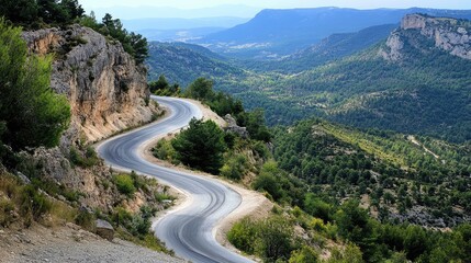 A winding mountain road with sharp curves, hugging the rocky terrain with a panoramic view of the valley below