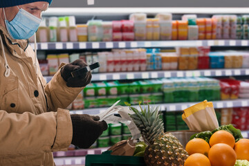 Male customer checking his paper receipt with magnifying glass after buying medication and pills. Pharmacy purchase: Receipt issued for payment of goods at checkout