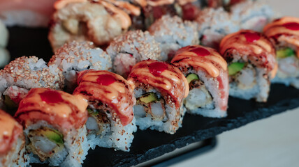 Delicious sushi rolls arranged elegantly on a black plate in a cozy restaurant setting