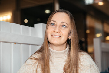 Portrait of a smiling woman in a cozy indoor setting with warm lighting