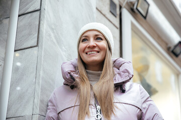 Winter fashion outdoors: smiling woman in purple jacket and knit hat