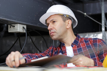 tradesman with clipboard inspecting roof space