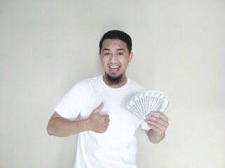 Cheerful asian man appreciated happy about earn money show thumb up