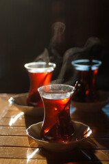 Beautiful backlit photo with shallow depth of field of Turkish tea served in traditional glasses  piping hot on a wooden table