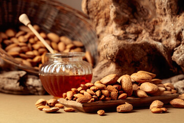 Almond nuts in a wooden dish and honey in a glass jar.