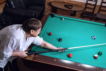 An elderly woman plays billiards in a billiard club.