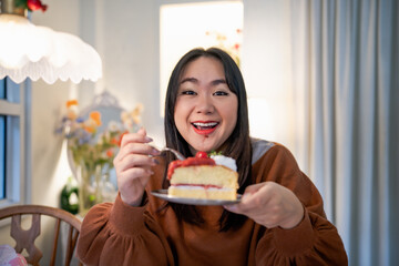 Beautiful Asian woman eating tasty cake. Teen girl eating the cake.