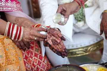 A traditional wedding ritual where a groom pours a sacred liquid into the bride's hand, symbolizing union and blessings in a spiritual ceremony.