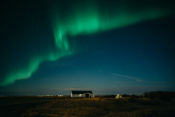 Dancing aurora borealis above Icelanding farm on the night sky