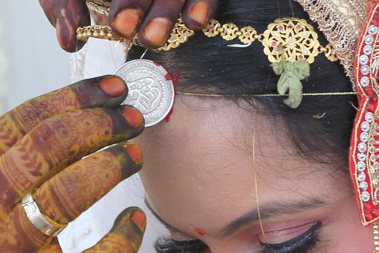 Indian wedding ritual where sindoor (vermilion) is being applied to the bride's hair parting, symbolizing the sacred bond of marriage.	