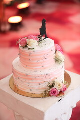 A charming wedding cake adorned with soft pink and white roses, topped with a silhouette of the couple, symbolizing their sweet union.
