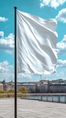 A white flag waves on a tall black pole against a vibrant city and blue sky