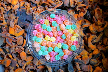 The edible background consists of a plastic dish with small colored candies standing on an apricot dryer.