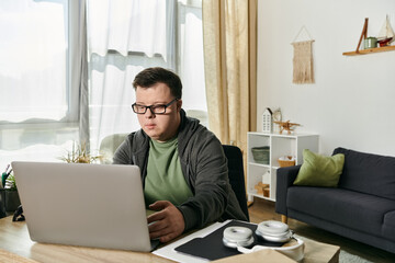 A young man with Down syndrome focuses intently on his laptop.