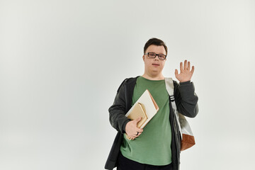 A young man with Down syndrome greets warmly while holding books at home.