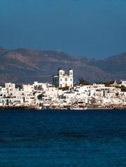 A picturesque view of Naoussa village in Paros Island, Greece, showcasing charming white-washed buildings with blue accents, narrow cobbled streets, and vibrant fishing boats in a crystal-clear harbor