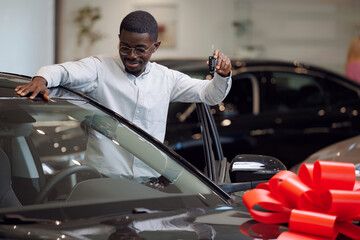 Handsome african american man is touch and test his new car and smiling. Business sales automobile in dealership