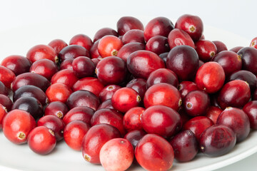 Red cranberries on a white plate, close-up.