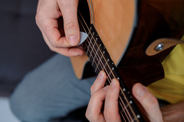 Fototapeta premium Guitarist on acoustic guitar playing melody. Close up musician instrument