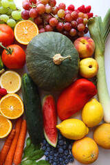 Various seasonal fruits and vegetables on white background. Summer and fall produce. Top view.