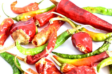 Red and green hot chili peppers lie on a white background.