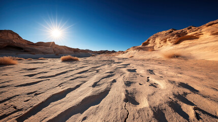 Sunny desert landscape with sand dunes and rugged rock formations under a clear blue sky