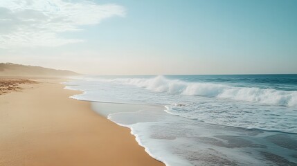 A wide shot of a beach with smooth sand and waves gently crashing onto the shore