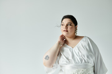 A stunning plus size bride in a flowing white dress showcases elegance and confidence against a muted backdrop.