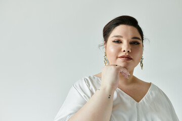 A beautiful plus size bride showcases her elegance with a white wedding dress and striking earrings.