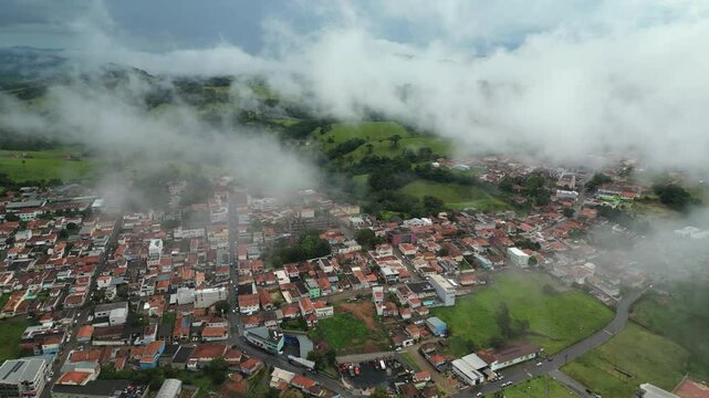 aerial dolly reverse view of Bueno Brandao town covered by foggy during a cold winter day - Small city in the countryside of Minas Gerais - Brazil