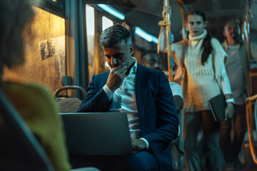 Businessman working on his laptop on a bus at night