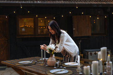 Brunette woman lighting up a candle on a wooden table