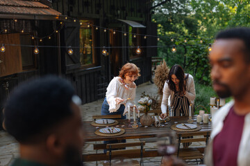 Two women igniting candles on a table in the garden