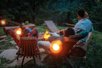 Rear view of four people enjoying a relaxing evening by a fire pit